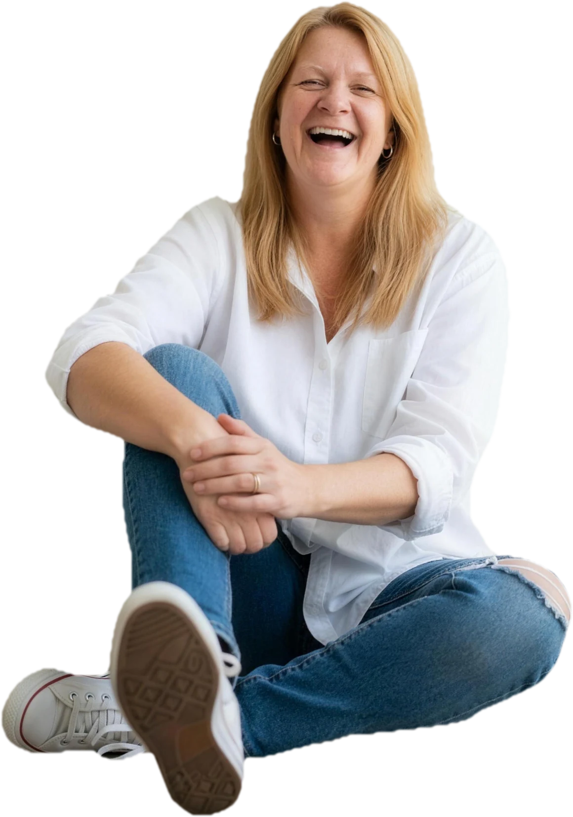 Jan sitting on the floor in a white shirt and jeans, laughing